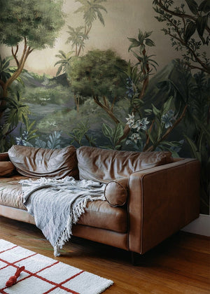 Vista em perspectiva de sala com sofá em couro caramelo manta off White tapete e Painel Paraíso das Orquídeas ao fundo